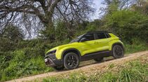 Jeep Avenger 4xe in Seitenansicht auf einem Schotterweg in natürlicher Umgebung.