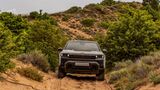 Jeep Compass 4xe auf einer sandigen Offroad-Strecke zwischen Dünen und Sträuchern in Frontansicht.