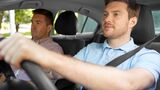 Junger Fahrschüler fährt unter Anleitung eines Fahrlehrers und bereitet sich auf den Pkw-Führerschein vor.