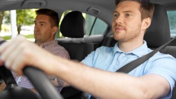 Junger Fahrschüler fährt unter Anleitung eines Fahrlehrers und bereitet sich auf den Pkw-Führerschein vor.