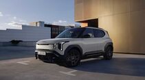 Kia EV2 Black Line in Weiß mit schwarzem Dach auf einem Parkdeck vor moderner Architektur.