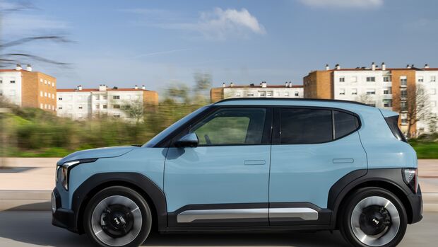 Kia EV2 in Frost Blue in seitlicher Ansicht während der Fahrt mit schwarzen Radhausverkleidungen und bündigen Türgriffen.