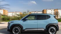 Kia EV2 in Frost Blue in seitlicher Ansicht während der Fahrt mit schwarzen Radhausverkleidungen und bündigen Türgriffen.