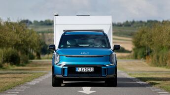 Kia EV9 Elektroauto zieht einen Wohnwagen auf einer Landstraße