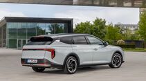 Kia K4 Sportswagon in Heckansicht auf einem Vorplatz vor moderner Architektur.