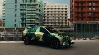 Kompakt-Crossover DS No7 mit Tarnfolierung steht auf urbaner Straße vor modernen Wohngebäuden.