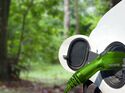 Ladekabel an einem Elektroauto vor grüner Waldkulisse, Symbol für alternative Antriebe und nachhaltige Firmenflotten.