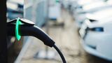 Ladekabel an einem Elektroauto vor weiteren Fahrzeugen an einer Ladesäule.