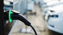 Ladekabel an einem Elektroauto vor weiteren Fahrzeugen an einer Ladesäule.