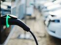 Ladekabel an einem Elektroauto vor weiteren Fahrzeugen an einer Ladesäule.