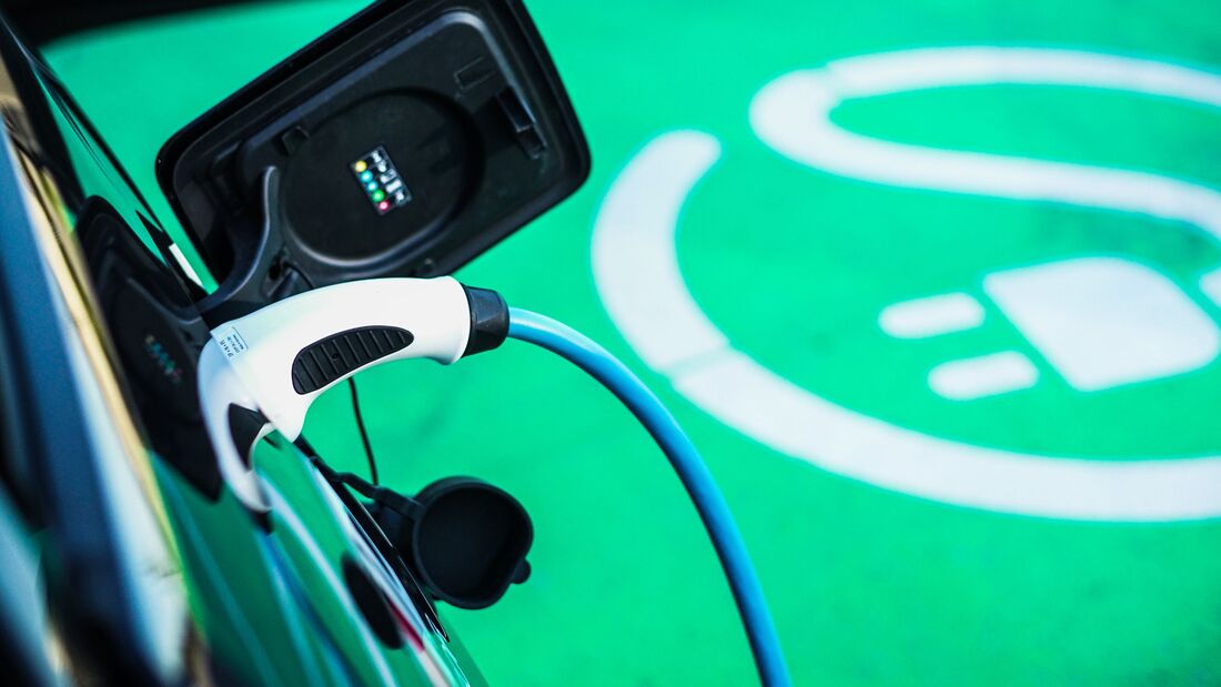 Ladestecker an einem Elektroauto vor markierter Ladeflaeche.