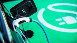 Ladestecker an einem Elektroauto vor markierter Ladeflaeche.