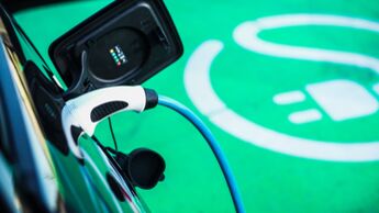 Ladestecker an einem Elektroauto vor markierter Ladeflaeche.