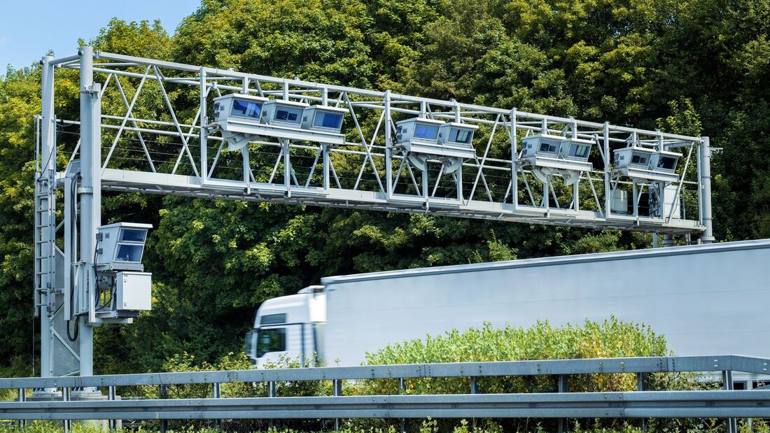 Lkw fährt unter einer Mautbrücke auf einer europäischen Autobahn hindurch.