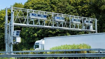 Lkw fährt unter einer Mautbrücke auf einer europäischen Autobahn hindurch.
