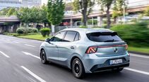 MG4 EV Urban Luxury in Hellblau aus der Heck-Seiten-Perspektive bei der Fahrt auf einer Stadtstraße.
