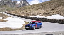 MINI Countryman JCW auf einer Passstraße mit Schneefeldern und Berglandschaft.