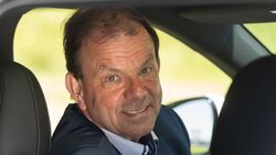 Markus Schrick, Deutschland-Geschäftsführer von Xpeng, sitzt im Fahrersitz eines Elektroautos und blickt über die Schulter zur Kamera.