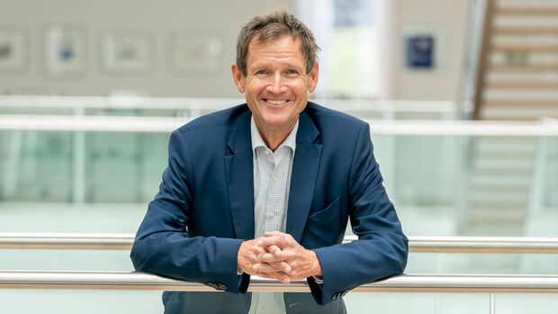 Martin Benzing im dunkelblauen Sakko in einem modernen Bürogebäude.
