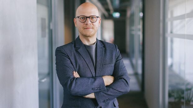Matas Buzelis von carVertical steht in einem Büroflur und blickt in die Kamera.