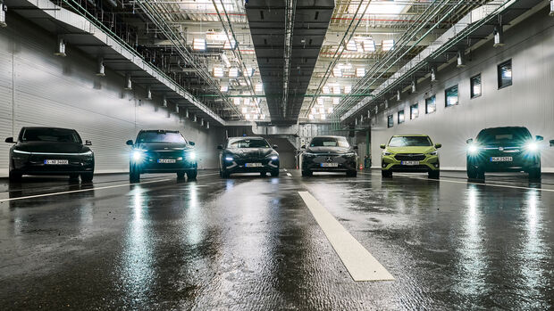 Mehrere Fahrzeuge stehen in einer Testhalle bei nasser Fahrbahn für ADAC-Versuche zu Assistenzsystemen unter realistischen Bedingungen