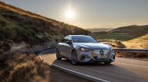 Mercedes C-Klasse Elektro fährt auf einer kurvenreichen Landstraße bei Sonnenlicht.