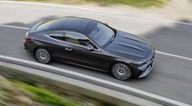 Mercedes CLE Coupé in dunkler Lackierung fährt aus erhöhter Perspektive auf einer Landstraße.
