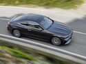 Mercedes CLE Coupé in dunkler Lackierung fährt aus erhöhter Perspektive auf einer Landstraße.