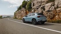 Mercedes GLA in Hellblau auf einer Küstenstraße, aufgenommen aus der Heckperspektive während der Fahrt.
