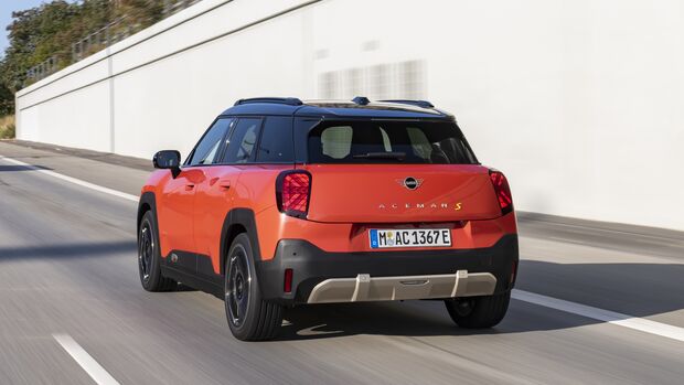 Mini Aceman SE in orange mit schwarzem Dach in Heck-Dreiviertelansicht während der Fahrt.