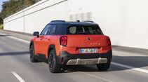 Mini Aceman SE in orange mit schwarzem Dach in Heck-Dreiviertelansicht während der Fahrt.