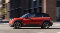Mini Aceman SE in orange und schwarz in seitlicher Ansicht während der Fahrt auf einer Straße.