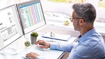 Mitarbeiter prüft digitale Rechnungen und Tabellen am Computer im Büro.