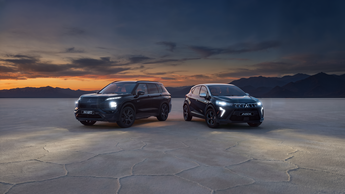 Mitsubishi ASX Black und Outlander Black stehen nebeneinander auf einer offenen Fläche bei Dämmerung.