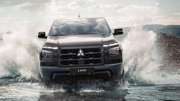 Mitsubishi L200 Pickup in der Frontansicht bei einer Wasserdurchfahrt mit aufspritzendem Wasser auf beiden Fahrzeugseiten.