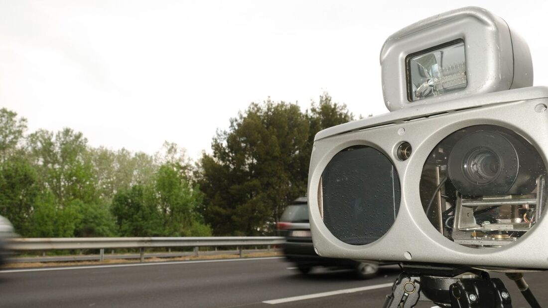 Mobiler Blitzer zur Geschwindigkeitsmessung am Straßenrand, vorbeifahrende Fahrzeuge unscharf, genutzt zur Darstellung von Messverfahren im Verkehrsrecht.