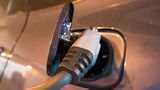 Nahaufnahme eines eingesteckten Ladekabels an der Ladebuchse eines Elektroautos.