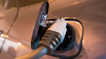Nahaufnahme eines eingesteckten Ladekabels an der Ladebuchse eines Elektroautos.