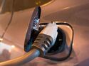 Nahaufnahme eines eingesteckten Ladekabels an der Ladebuchse eines Elektroautos.