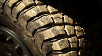 Nahaufnahme eines grobstolligen Offroad-Reifens eines Feuerwehr-INEOS-Grenadier mit sichtbarer Verschmutzung.