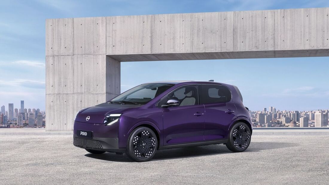 Nissan Pixo in Violett als Elektro-Kleinwagen in Front-Seitenansicht vor moderner Betonarchitektur und Stadtkulisse.