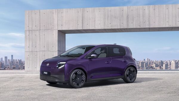 Nissan Pixo in Violett als Elektro-Kleinwagen in Front-Seitenansicht vor moderner Betonarchitektur und Stadtkulisse.