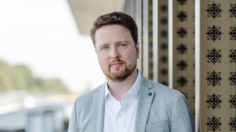 Oliver Adrian, COO und CRO von chargecloud, im Porträt vor moderner Gebäudearchitektur.
