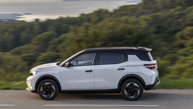 Opel Frontera Electric Extended Range in weiss, frontansicht, fahrend auf kurviger kuestenstrasse mit meer im hintergrund