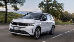 Opel Frontera Electric Extended Range in weiss mit schwarzem dach, frontansicht schraeg, fahrend auf landstrasse