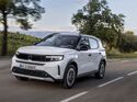 Opel Frontera Electric Extended Range in weiss mit schwarzem dach, frontansicht schraeg, fahrend auf landstrasse
