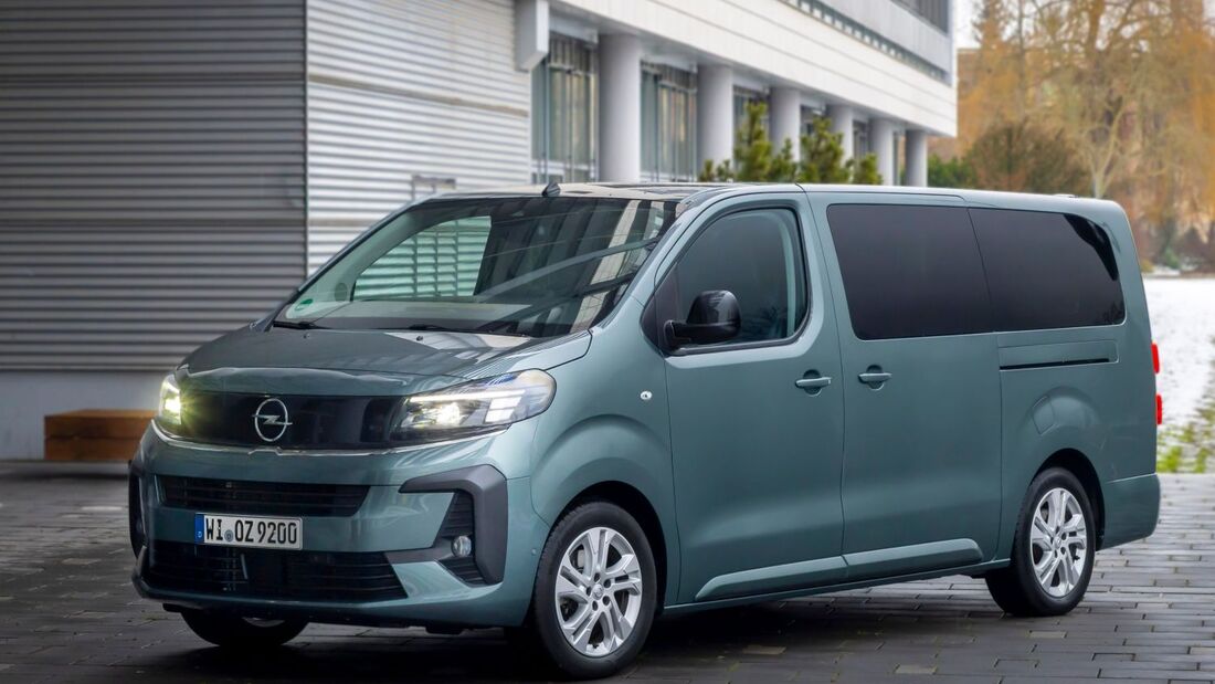 Opel Zafira Van in Frontansicht auf gepflastertem Vorplatz vor modernem Gebäude mit eingeschaltetem Fahrlicht.