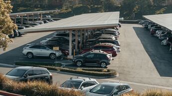 Parkplatz mit mehreren abgestellten Fahrzeugen unter Carports als Symbol für Poolfahrzeuge und Corporate Carsharing.