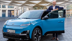 Pascal Michaeli steht neben einem Nissan Micra Elektroauto in urbaner Umgebung