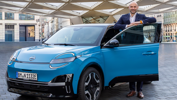 Pascal Michaeli steht neben einem Nissan Micra Elektroauto in urbaner Umgebung